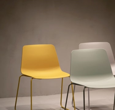 Picture of three chairs, one yellow, other beige and the last one white.